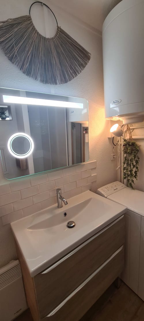 Salle de bain moderne aux Suites Du Port, Arcachon avec miroir illuminé, lavabo blanc et décoration murale en tissage