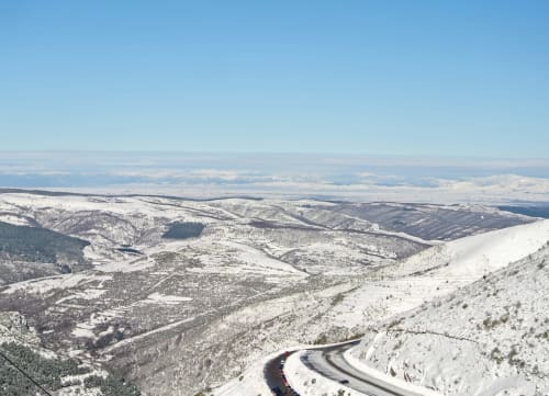Paisaje de montaña nevada cerca del Hotel del Trueno en Ezcaray con carretera sinuosa y valles boscosos