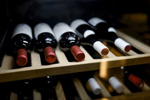 Botellas de vino con cápsulas rojas almacenadas en estanterías de madera en la bodega del Hotel del Trueno, Ezcaray