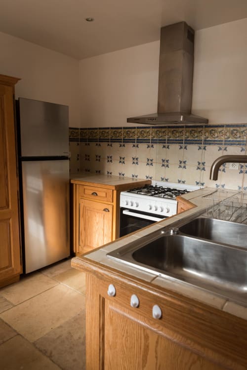 Cuisine moderne de la maisonnette Domaine Chapelle avec armoires en bois, cuisinière à gaz, évier inox et touches de bleu décoratives
