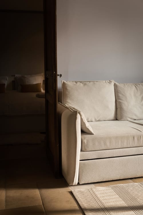 Canapé rembourré crème avec coussins dans une chambre de la Domaine Chapelle, lumière naturelle sur les planchers de bois