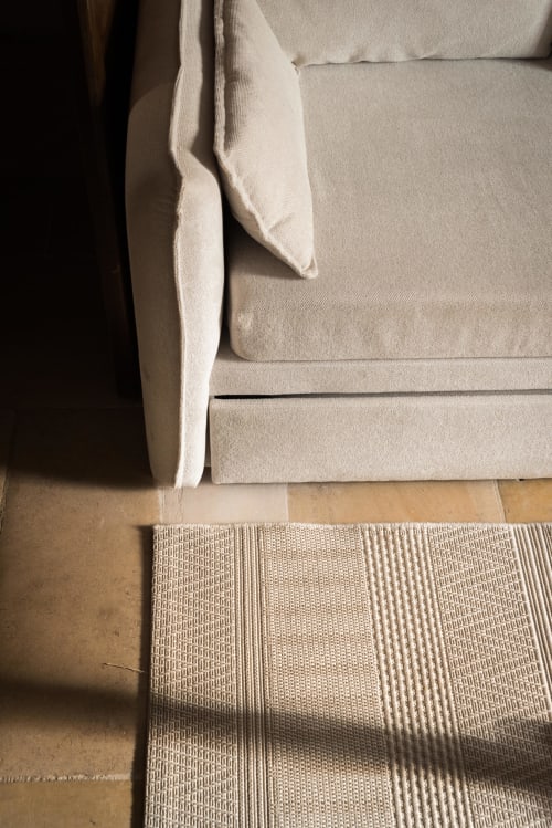 Canapé en tissu crème à la maisonnette Domaine Chapelle, avec tapis rayé naturel sur parquet