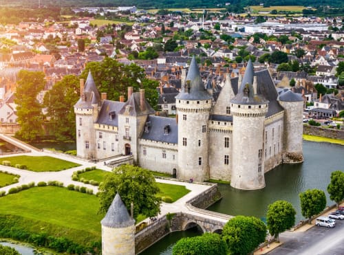 Château médiéval entouré de douves et jardins paysagés dominant la ville de Pierrefitte-sur-Sauldre