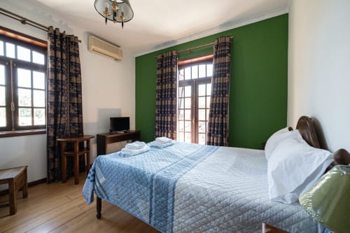 Quarto duplo espaçoso da pousada Casa Augusta em Penafiel com roupa de cama azul, parede verde, piso de madeira e moderno