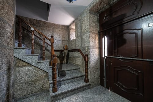 Escada de pedra com corrimãos de madeira subindo pela Casa Augusta, pousada em Penafiel, Portugal