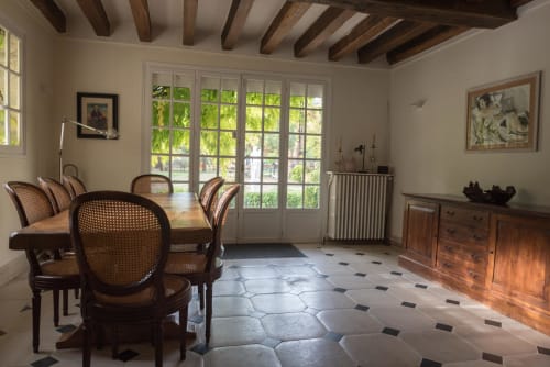 Élégante salle à manger du Domaine Chapelle avec plafond à poutres apparentes, chaises d'époque et vue sur le jardin par portes-fenêtres