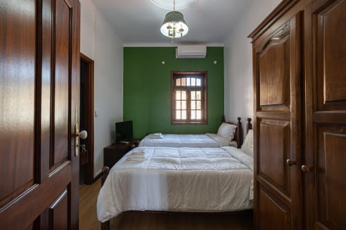 Camas geminadas na Suite 18 da Casa Augusta, Penafiel - parede de destaque verde, portas de madeira, ar condicionado
