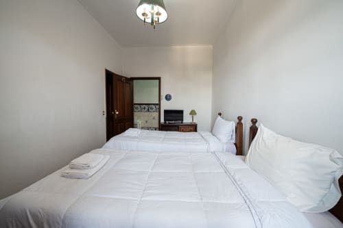 Quarto duplo limpo da pousada Casa Augusta em Penafiel com roupa de cama branca, móveis de madeira e comodidades modernas