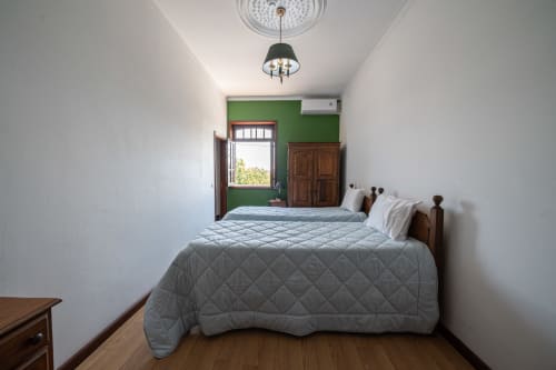 Luminoso quarto duplo na Casa Augusta hostel em Penafiel com parede verde, camas de madeira e luz natural da porta