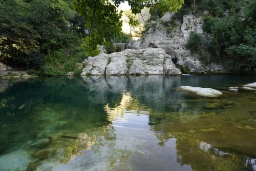 Piscina de agua cristalina turquesa rodeada de acantilados de piedra caliza y exuberante vegetación en Casa Rural Garden Suites de Xàtiva
