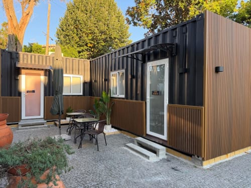 Quarto moderno em container preto no hostel Casa Augusta em Braga, Portugal, com acabamentos em madeira e área de estar ao ar livre