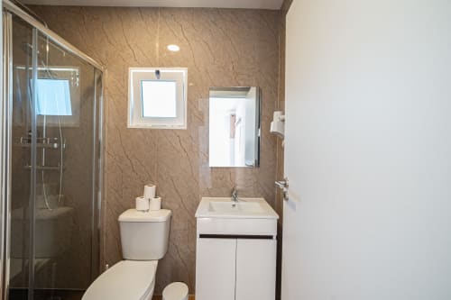 Banheiro moderno no hostel Casa Augusta em Braga, Portugal, com box de chuveiro, pia branca, vaso sanitário e