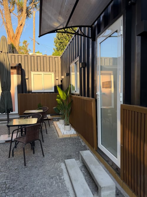 Pátio do quarto C5 da Casa Augusta, albergue em Braga, com móveis, planta em vaso e toldo preto