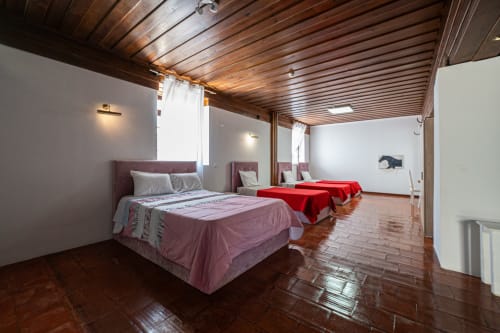 Suite Familiar da Casa Augusta em Penafiel com múltiplas camas, teto de madeira, piso de terracota e comodidades modernas