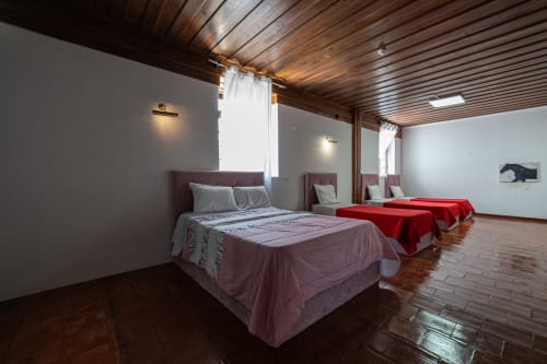 Suíte do hostel Casa Augusta Penafiel com múltiplos leitos, teto de madeira e comodidades modernas