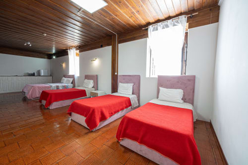 Quarto da suíte familiar no albergue Casa Augusta em Penafiel com quatro camas, cobertores vermelhos e teto de madeira