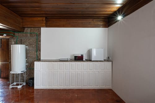Cozinha do hostel Casa Augusta com armários brancos, eletrodomésticos e aquecedor em Penafiel, Portugal