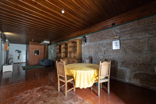 Área de refeições da Suite Familiar do hostel Casa Augusta com mesa redonda, cadeiras de madeira, paredes de pedra e teto de madeira em Penafiel