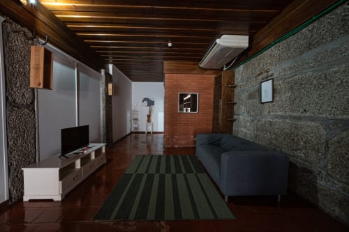 Suíte Familiar Moderna T1 na Casa Augusta hostel em Penafiel com teto em madeira escura, parede de tijolos aparentes e TV de tela plana,