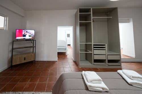 Quarto C5 do Hostel Casa Augusta com cama, guarda-roupa embutido, TV e piso de azulejo terracota em Braga, Portugal