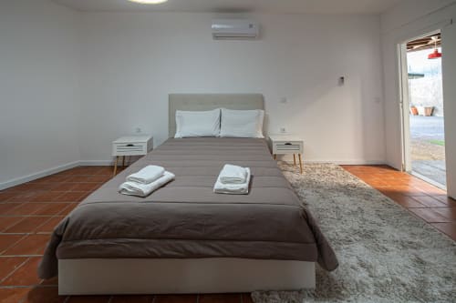 Quarto moderno na pousada Casa Augusta em Braga, Portugal com cama de casal, mesas-de-cabeceira brancas, piso de terracota, ar-condicionado e