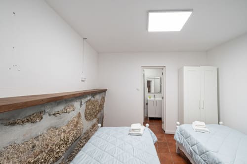 Quarto C5-Mariquinha do hostel Casa Augusta em Braga, Portugal com duas camas e detalhe de parede em pedra rústica