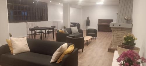 Salón del Hotel del Trueno en Ezcaray con sofás oscuros, zona de comedor, piano y plantas en macetas