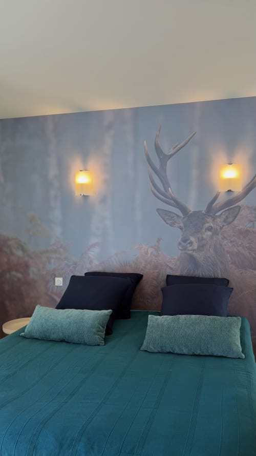 Chambre douillette du Cloffy B&B : literie turquoise, fresque de cerfs, appliques chaleureuses et vue sur forêt brumeuse
