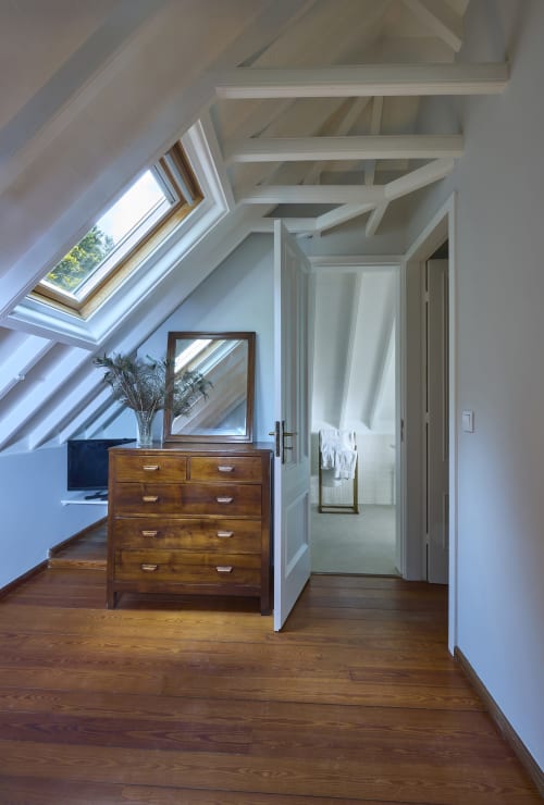 Quarto aconchegante na cobertura da Casa Dos Barcos Furnas com cômoda de madeira, claraboias, vigas expostas e assoalho de madeira