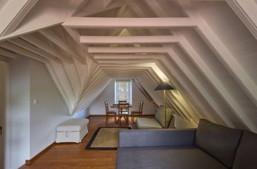 Sala de estar clara no sótão da Cottage Furnas com vigas expostas, piso de madeira, sofá, zona de refeições e vista pela janela