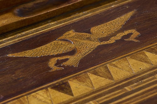 Detalhe de marchetaria em madeira com desenho de águia em superfície de madeira escura na casa de hóspedes Casa Dos Barcos Furnas