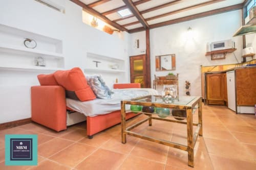 Bright Strelitzia Agaete studio apartment at MBM hostel in Gran Canaria with orange sofa bed, wooden table, and kitchen area