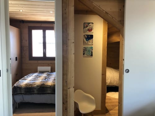 Chambre chaleureuse de l'appartement La Frontièra aux Tanières de Montgenèvre avec poutres en bois, lit et décoration montagnarde