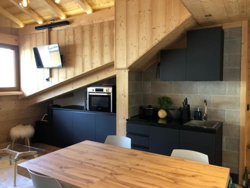 Cuisine moderne de l'appartement ski aux Tanières de Montgenèvre : meubles noirs, poutres bois, table à manger et télévision