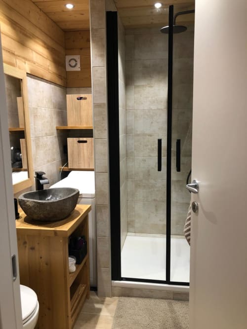 Salle de bain moderne de l'appartement La Frontièra aux Tanières avec vasque en pierre, douche à l'italienne, meuble de rangement en bois et chauffage