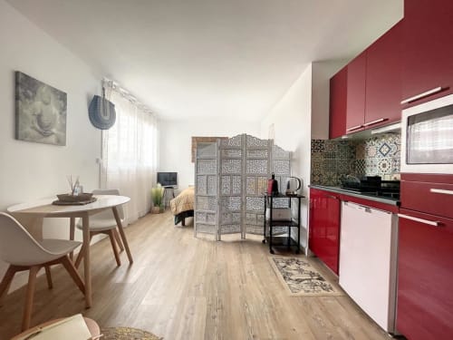 Petit studio moderne à Arcachon avec cuisine aux placards rouges, coin repas et claustra décoratif