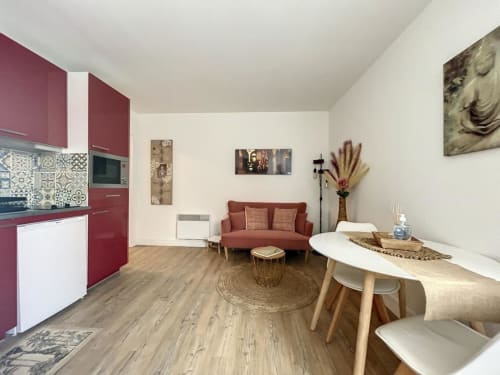 Studio aux Suites Du Port à Arcachon : cuisine bordeaux, canapé, table à manger en bois, vue sur la ville