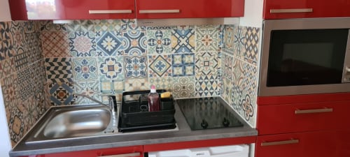 Kitchenette moderne aux armoires rouges, carreaux marocains motifs, évier et cuisinière en acier inoxydable aux Suites Du Port
