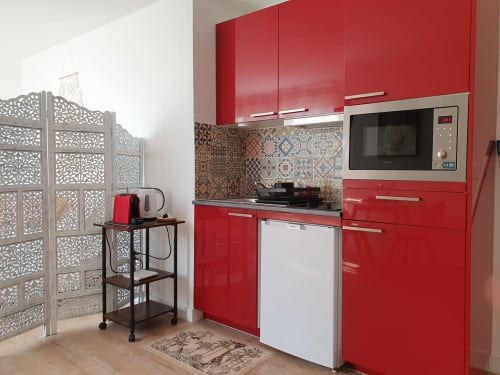 Cuisine rouge moderne dans la Suite studio des Suites Du Port, Arcachon avec crédence à motifs et électroménagers inox