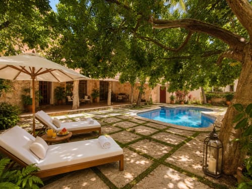 Hacienda Las Golondrinas villa courtyard in Isla Mujeres with pool, loungers, umbrella, and mature trees