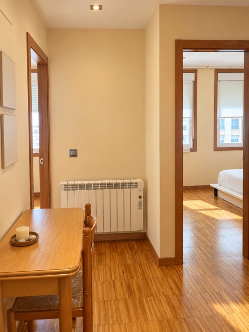 Pasillo moderno de apartamento en Baiona con suelo de madera, paredes amarillas, radiador y puertas hacia dormitorio y sala