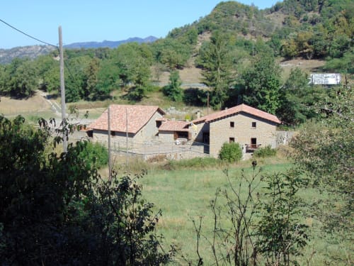 Hostal Collsacabra a L'Esquirol, allotjament rústic de pedra entre muntanyes forestals i paisatge rural ondulant