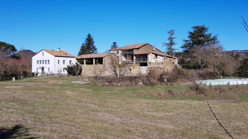 Hostal Collsacabra a L'Esquirol amb edificis de pedra i blancs envoltats de paisatge rural i arbres