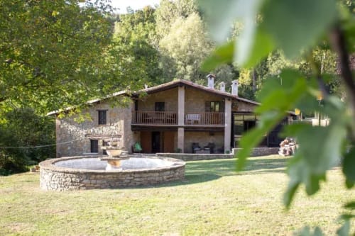 Hostal Collsacabra a L'Esquirol: construcció de pedra, pati amb foguera i bosc al voltant