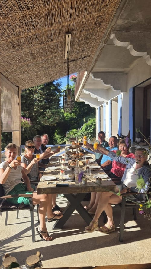 Groupe dînant sous la véranda couverte de La Maison Du Chevalier, Marat, France avec vue sur le jardin