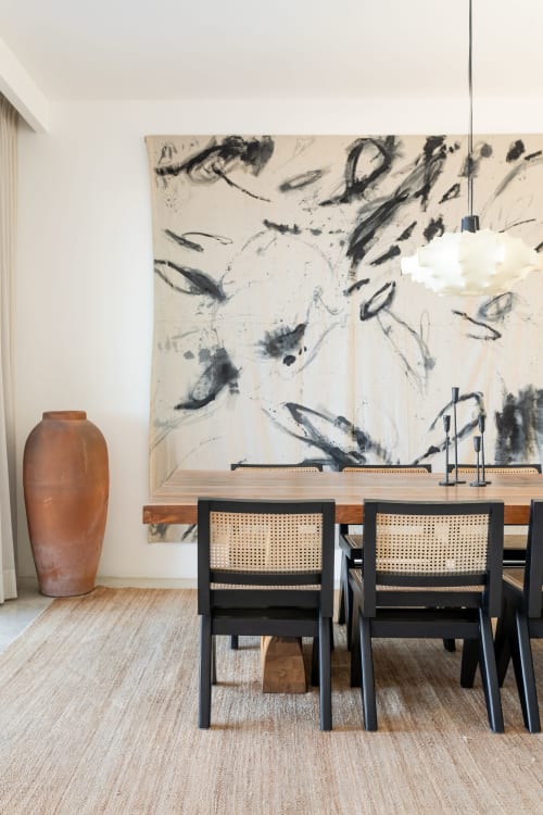 Modern dining area at Casa Copal cottage with black chairs, wooden table, and abstract artwork overlooking Isla Mujeres
