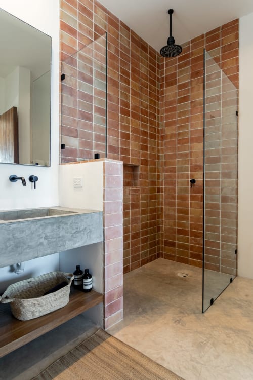 Modern bathroom in Casa Copal cottage at Isla Mujeres with terracotta brick tiled shower, concrete sink, and black fixtures