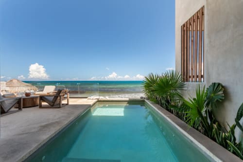 Beachfront Casa Copal in Isla Mujeres with turquoise pool, sea view, lounge chairs, and tropical plants overlooking Caribbean