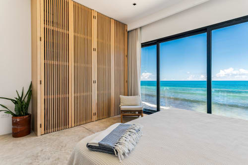 Modern beachfront bedroom at Isla Mujeres cottage with ocean view, wooden slat wardrobe, and direct beach access