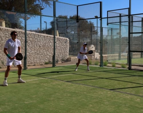 Deux joueurs sur le court de padel à Villa des Arganiers, Sidi Kaouki, Essaouira avec murs en pierre et filet d'enceinte